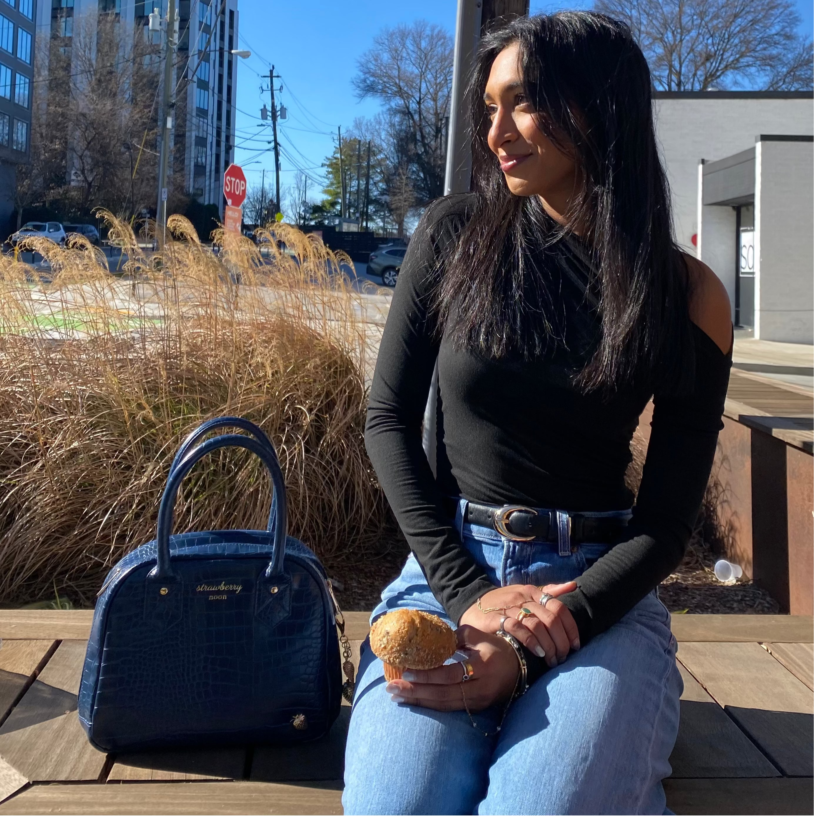 Woman sitting on a bench with a blue handbag and bread, urban setting
