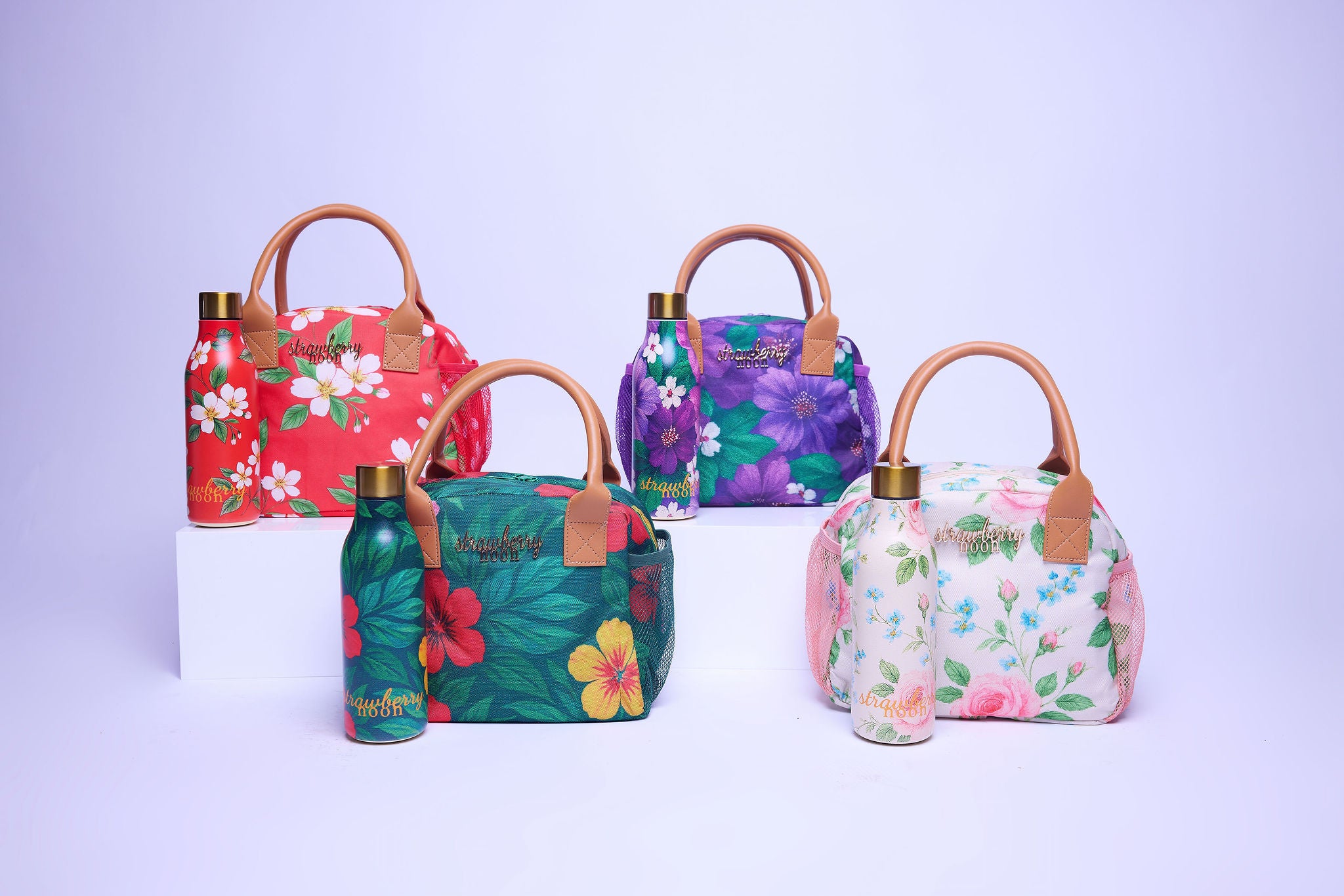 Set of colorful floral-patterned handbags with matching water bottles on a light purple background